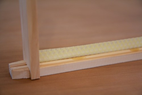 A starter strip of comb is 'glued' into the top bar, using melted wax.