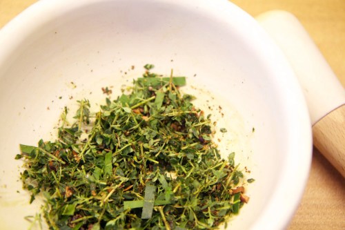 Lightly crushing the spice and herb mix.